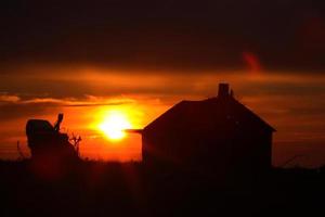 coucher de soleil derrière les vieux bâtiments de ferme de la saskatchewan photo