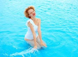 portrait de femme rousse souriante profitant de la vie en maillot de bain blanc dans la piscine photo