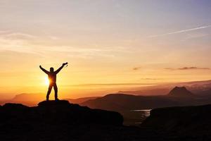 silhouette d'un homme au sommet d'une montagne. silhouette de personne sur le rocher. concept de sport et de vie active photo