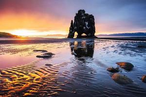 est un rocher spectaculaire dans la mer sur la côte nord de l'Islande. les légendes disent que c'est un troll pétrifié. sur cette photo hvitserkur se reflète dans l'eau de mer après le coucher du soleil de minuit