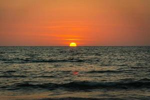 coucher de soleil lumineux avec un grand soleil jaune sous la surface de la mer photo