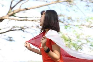 femme asiatique excitée tenant le drapeau indonésien le jour de l'indépendance de l'indonésie photo
