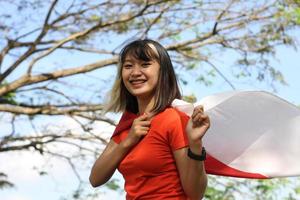 femme asiatique excitée tenant le drapeau indonésien le jour de l'indépendance de l'indonésie photo