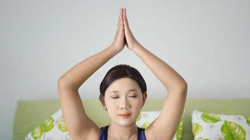 femme asiatique pratiquant le yoga à la maison faisant un mouvement de la main photo