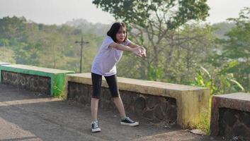 une jeune femme asiatique s'étire avant de faire du jogging et de courir le matin photo