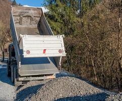 renversement de gravier provenant de camionsvaches avec veaux broutant photo