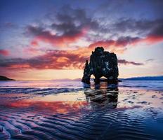 est un rocher spectaculaire dans la mer sur la côte nord de l'Islande. les légendes disent que c'est un troll pétrifié. sur cette photo hvitserkur se reflète dans l'eau de mer après le coucher du soleil de minuit