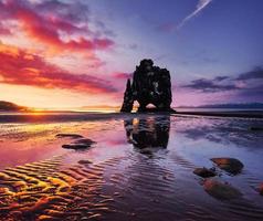 est un rocher spectaculaire dans la mer sur la côte nord de l'Islande. les légendes disent que c'est un troll pétrifié. sur cette photo hvitserkur se reflète dans l'eau de mer après le coucher du soleil de minuit