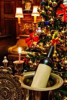 bouteille de vin dans la célébration des vacances de noël. décoration de salon en décembre festive, saison d'hiver. beau fond. intérieur de la salle d'ornement de lumière dorée. photo