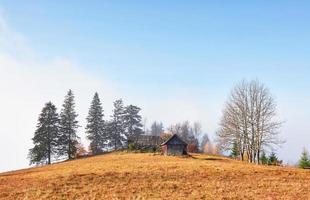 lever du soleil au-dessus de la vallée brumeuse de haute montagne avec de vieilles maisons en bois sur une colline dans une forêt de montagne photo