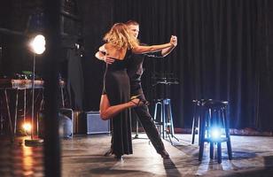 danseurs habiles se produisant dans la pièce sombre sous la lumière photo