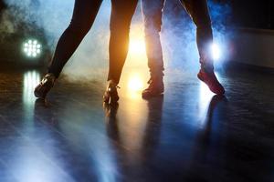 danseurs habiles se produisant dans la pièce sombre sous la lumière et la fumée du concert. belles jambes féminines et masculines en danse active photo