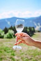 main avec un verre de vin mousseux sur fond de montagnes photo