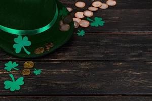 chapeau de lutin et feuilles de trèfle de trèfle sur fond de bois marron. photo