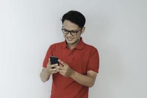 Un jeune homme asiatique intelligent est heureux et souriant lorsqu'il utilise un smartphone en arrière-plan studio photo