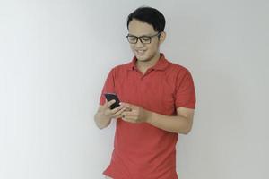 Un jeune homme asiatique intelligent est heureux et souriant lorsqu'il utilise un smartphone en arrière-plan studio photo