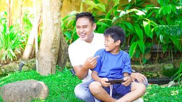 papa et fils jouent à des jeux mobiles dans le parc photo