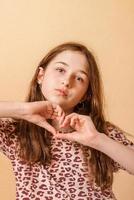 portrait d'enfant. adolescente montre un coeur sur fond beige. photo