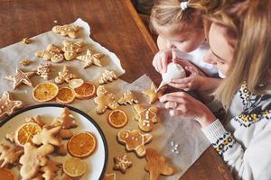 maman et fille décorent le biscuit de noël avec du sucre blanc photo