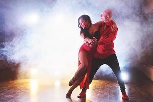 danseurs habiles se produisant dans la pièce sombre sous la lumière et la fumée du concert. couple sensuel exécutant une danse contemporaine artistique et émotionnelle photo