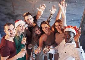 la nouvelle année arrive. groupe de jeunes multiethniques joyeux dans des chapeaux de père Noël à la fête, posant un concept de style de vie émotionnel photo