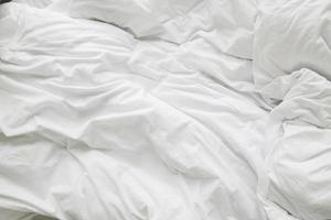 couverture malpropre froissée et oreiller blanc dans la chambre après s'être réveillé le matin, après avoir dormi dans une longue nuit. photo