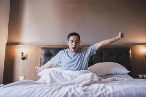 portrait d'homme bâillant tout en étirant ses bras dans son lit photo