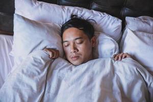 gros plan homme dormant sur le lit avec une couverture blanche photo