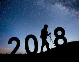 silhouette jeune homme randonneur pour le nouvel an 2018 fond de la voie lactée sur un ton de ciel sombre étoile brillante photo
