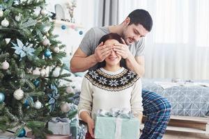 jeune couple célébrant Noël. un homme a soudainement présenté un cadeau à sa femme. le concept de bonheur et de bien-être familial