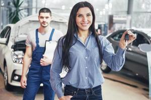 une jeune femme prend une voiture du centre de service automobile. elle est contente car le travail est parfaitement fait photo