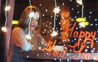 belle jeune femme assise dans un café, buvant du café. noël, bonne année, saint valentin, concept de vacances d'hiver photo