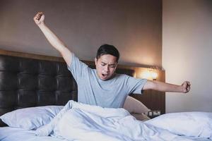 portrait d'homme bâillant tout en étirant ses bras dans son lit photo