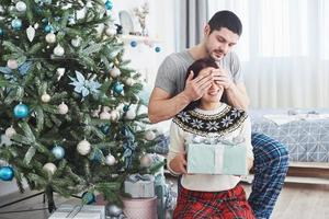 jeune couple célébrant Noël. un homme a soudainement présenté un cadeau à sa femme. le concept de bonheur et de bien-être familial