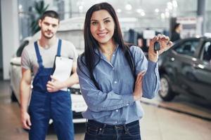 une jeune femme prend une voiture du centre de service automobile. elle est contente car le travail est parfaitement fait photo