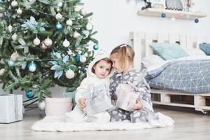 deux petites soeurs ouvrent leurs cadeaux à l'arbre de noël le matin sur le pont photo