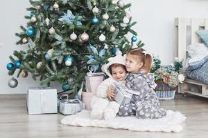 deux petites soeurs ouvrent leurs cadeaux à l'arbre de noël le matin sur le pont photo