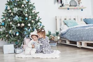 deux petites soeurs ouvrent leurs cadeaux à l'arbre de noël le matin sur le pont photo