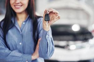 une jeune femme prend une voiture du centre de service automobile. elle est contente car le travail est parfaitement fait photo