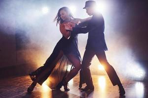 danseurs habiles se produisant dans la pièce sombre sous la lumière et la fumée du concert. couple sensuel exécutant une danse contemporaine artistique et émotionnelle photo