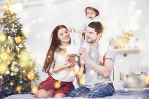 famille heureuse à noël le matin en ouvrant des cadeaux ensemble près du sapin. le concept de bonheur et de bien-être familial photo