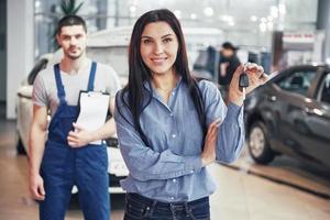 une jeune femme prend une voiture du centre de service automobile. elle est contente car le travail est parfaitement fait photo