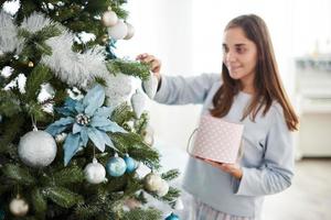 belle jeune fille en pyjama décorant le sapin de noël photo