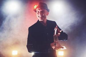 magicien montrant un tour avec des cartes à jouer. magie ou dextérité, cirque, jeux d'argent. prestidigitateur dans une pièce sombre avec brouillard photo