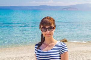 portrait en gros plan d'une jeune belle fille avec un t-shirt rayé et des lunettes de soleil regardant la caméra et souriant photo