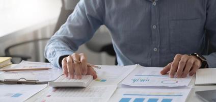 gros plan main d'homme d'affaires à l'aide d'une calculatrice et travaillant avec un ordinateur portable calculer sur la comptabilité financière au coffeeshop outdor.concept de comptabilité financière photo