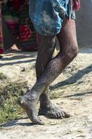 jambe d'un ouvrier avec de la boue partout travaillant sur la pêche de l'étang à poissons photo