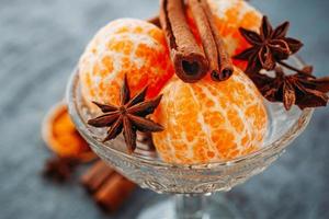 mandarine, bâtons de cannelle et anis dans un bol en verre photo