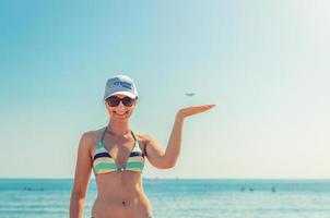 jeune belle fille en bikini, lunettes de soleil et casquette sur la plage de larnaca posant photo