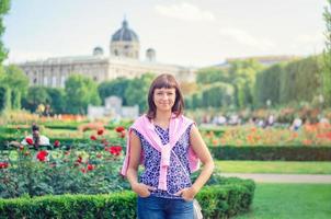 jeune belle fille caucasienne avec chemise fleurie regardant la caméra, posant et souriant dans le parc jardin de volksgarten photo